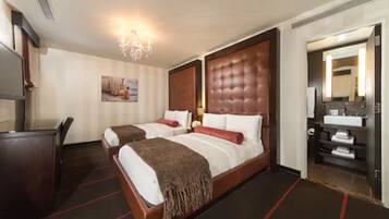 A hotel room with two beds, a desk, a mirror, and a bathroom.