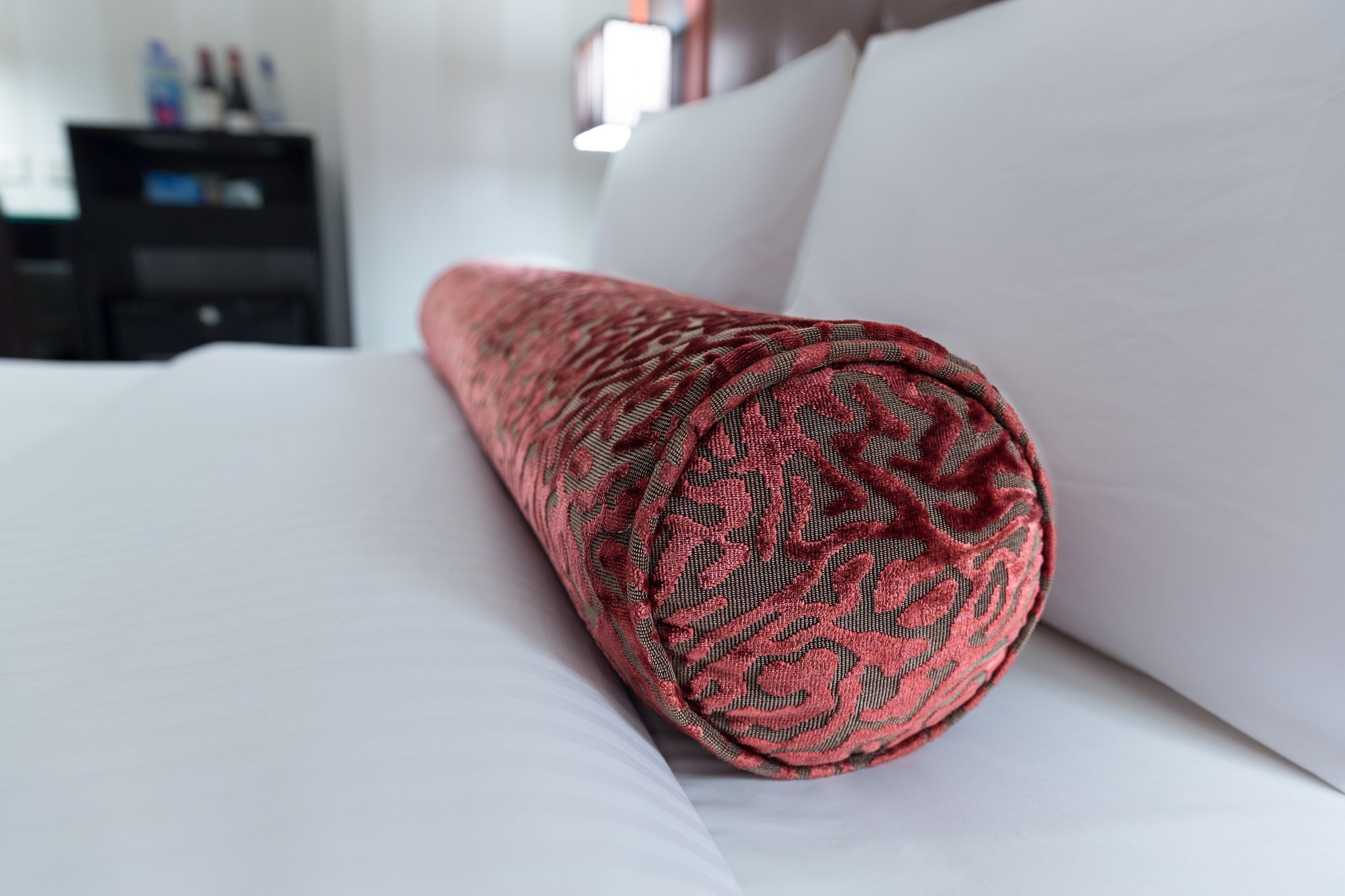 Een net opgemaakt bed met een opgerolde, gestreepte deken.