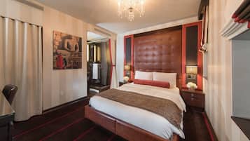 Una habitación de hotel con una cama grande, un cabecero de madera, una araña y un cuadro en la pared.