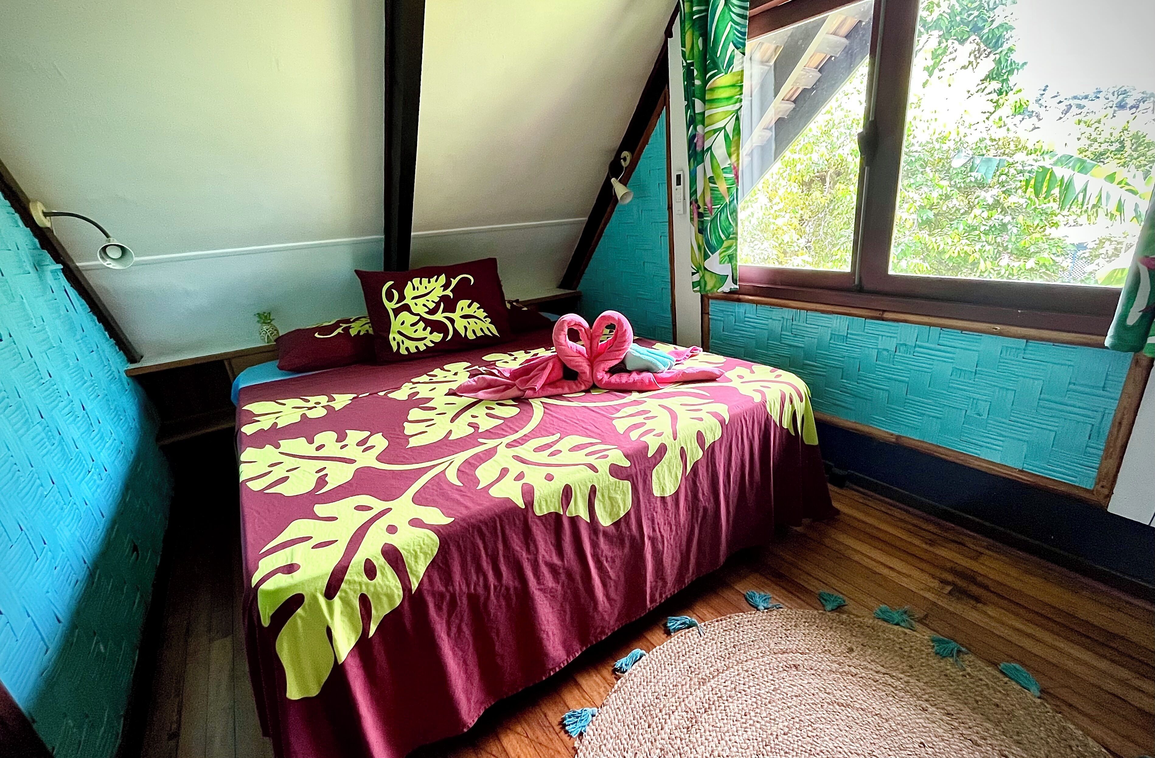 A bedroom with a bed, a window, and a view of greenery outside.