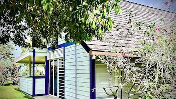 A modern house with a blue exterior, a covered porch, and a small garden area.