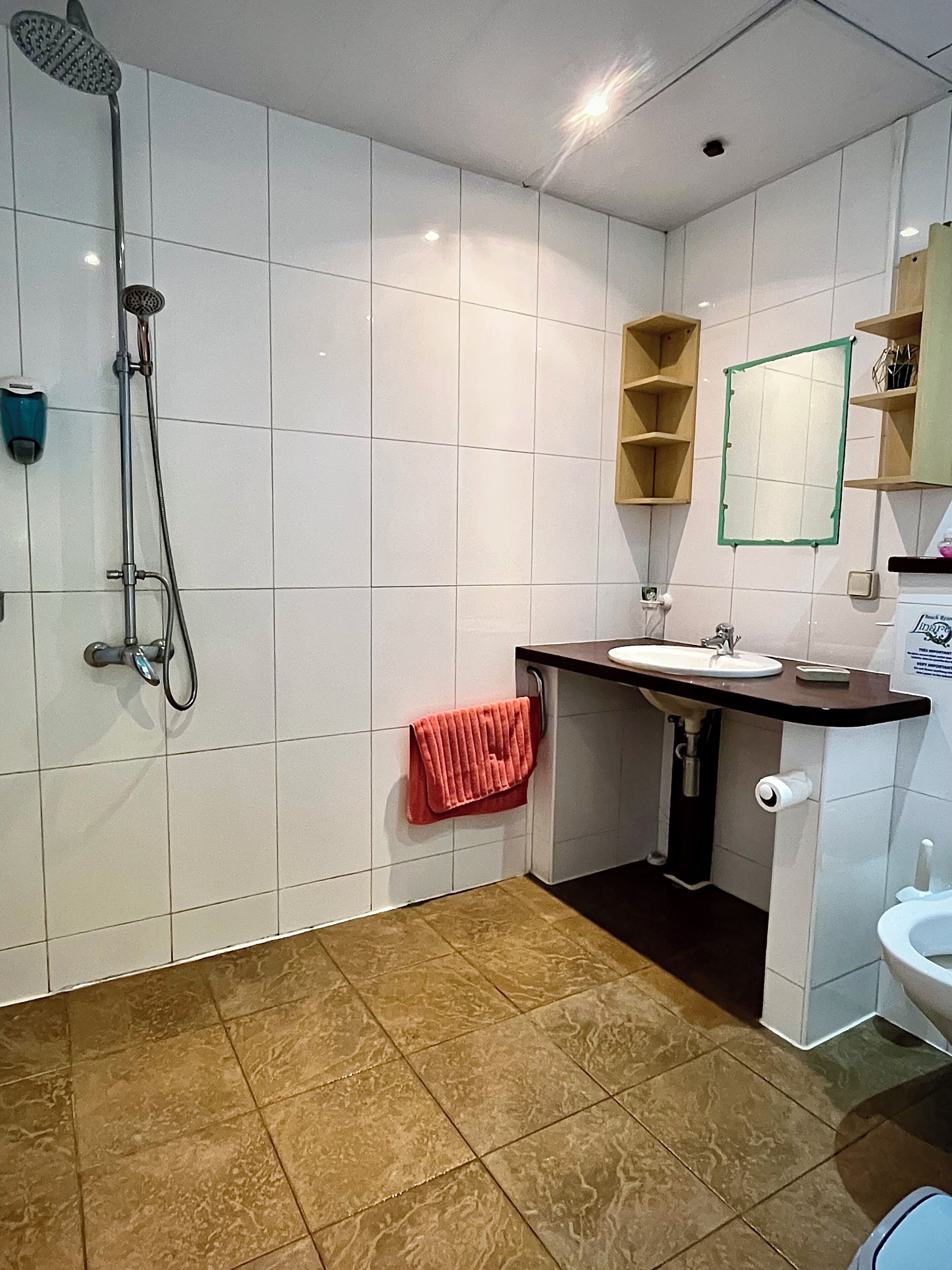 A modern bathroom with white tiles, a shower, a sink, and a toilet.