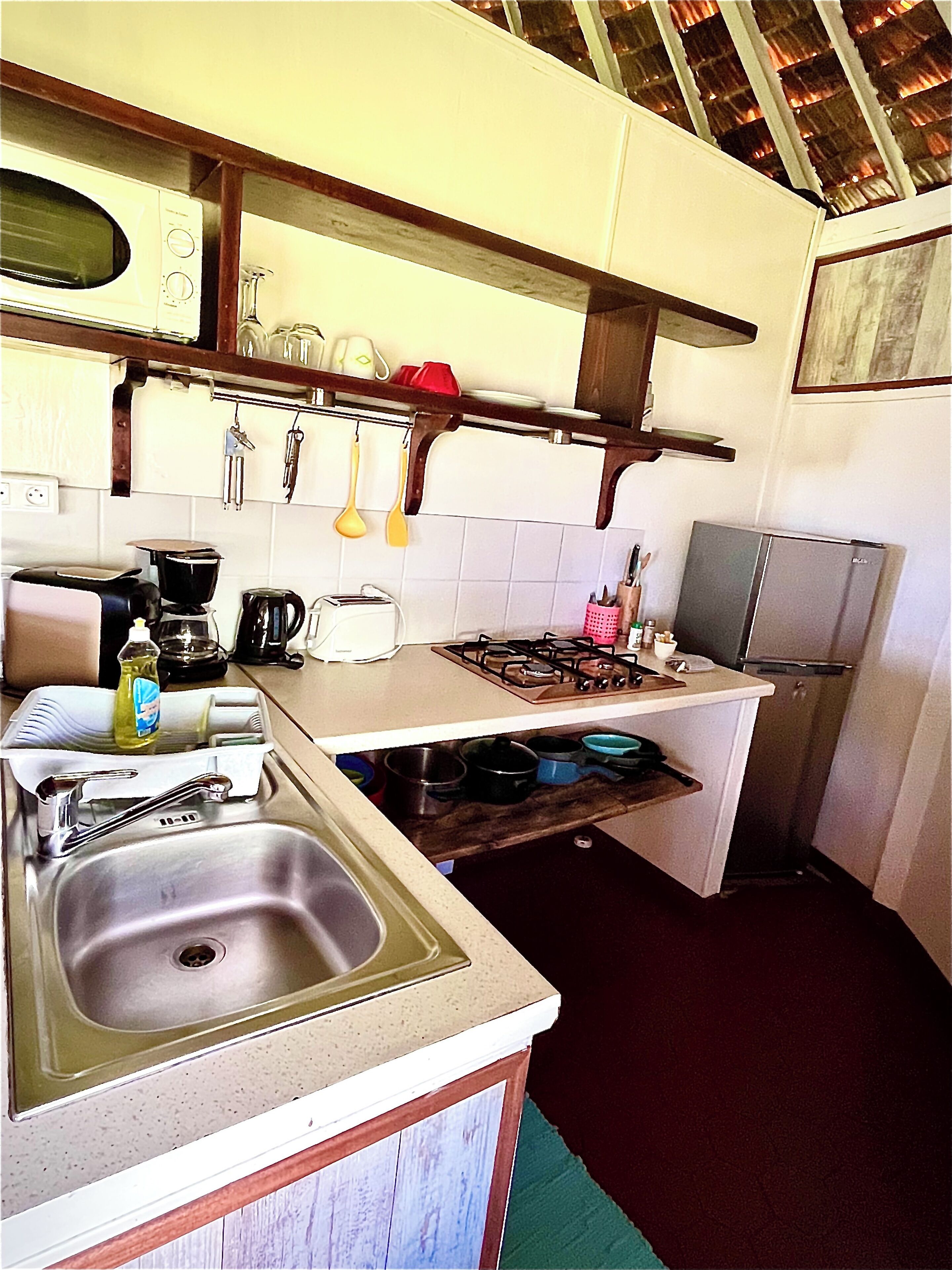 Una cocina compacta con lavamanos, estufa y diversos utensilios.