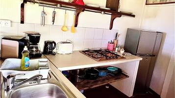 Una cocina compacta con lavamanos, estufa y diversos utensilios.
