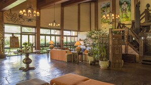 A spacious lobby with a high ceiling, wooden beams, and multiple chandeliers. There are several seating areas with tables and chairs, and large windows allowing natural light. - Hotel Bomtempo Itaipava (Petrópolis)