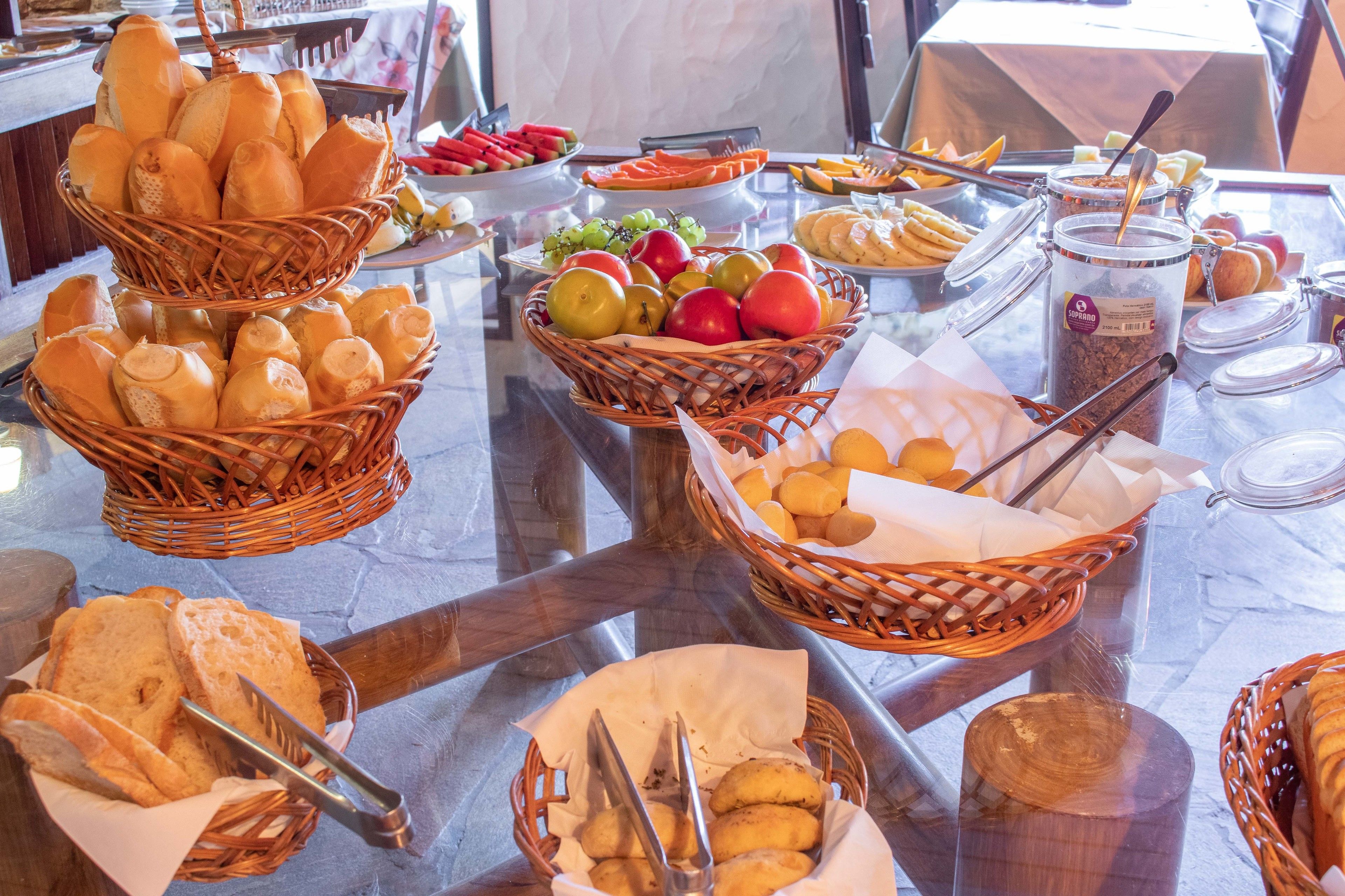 A buffet with various food items including bread, fruits, and pastries.