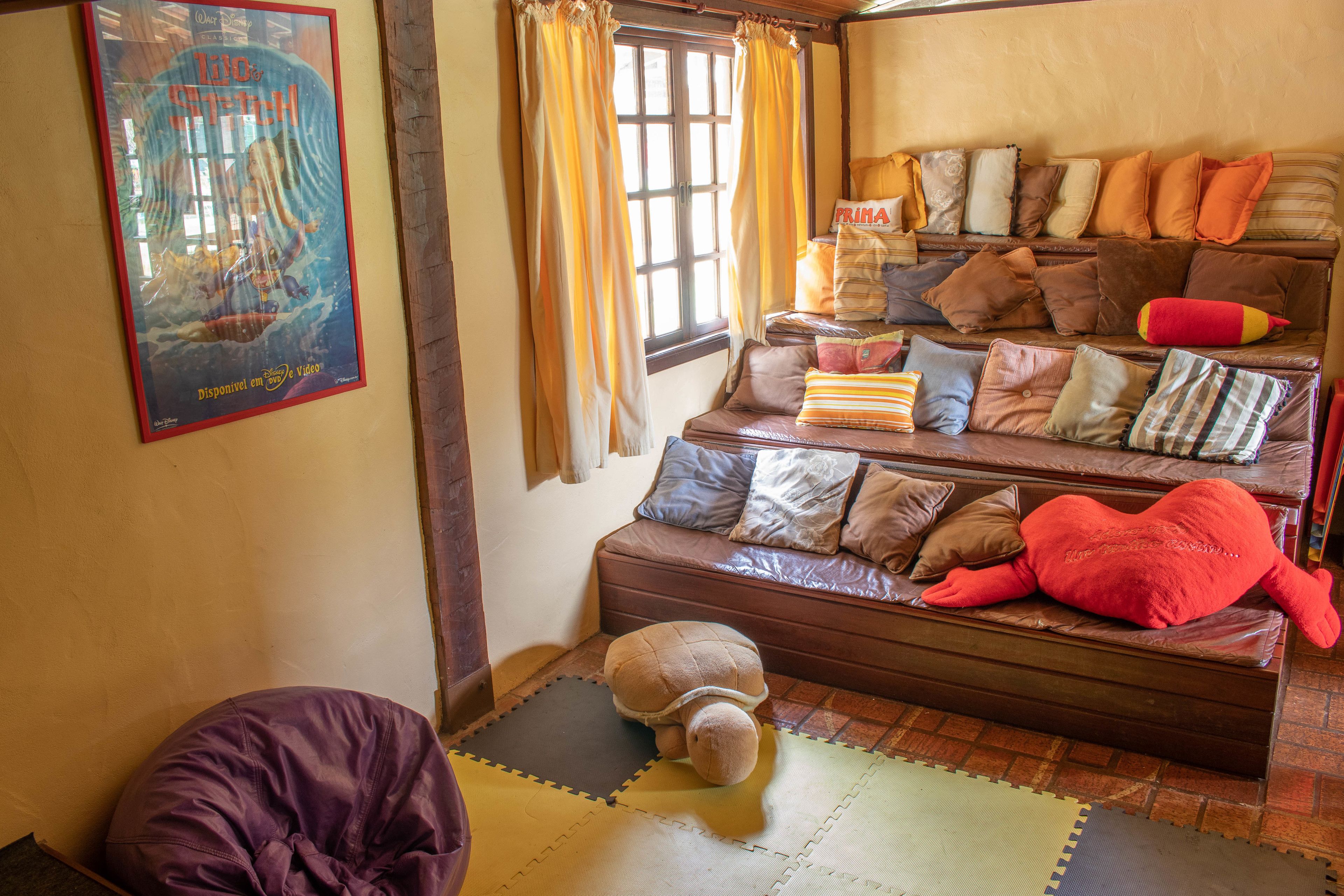 Une pièce confortable avec un canapé, un grand jouet en peluche et une affiche accrochée au mur.