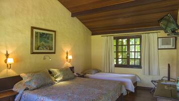 A bedroom with two beds, a wooden ceiling, a painting on the wall, and a window with curtains.