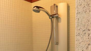 A shower with a handheld showerhead and control knobs.