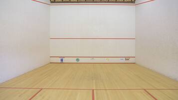 Una cancha de squash con piso de madera y líneas delimitadoras rojas.