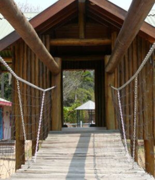 A wooden pedestrian bridge with a metal railing and a covered walkway. - Hotel Bomtempo Itaipava (Petrópolis)