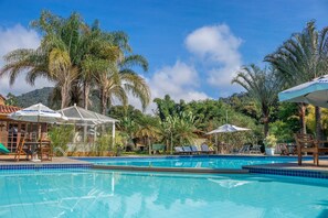 Een buitenzwembad, parasols bij het zwembad en ligstoelen