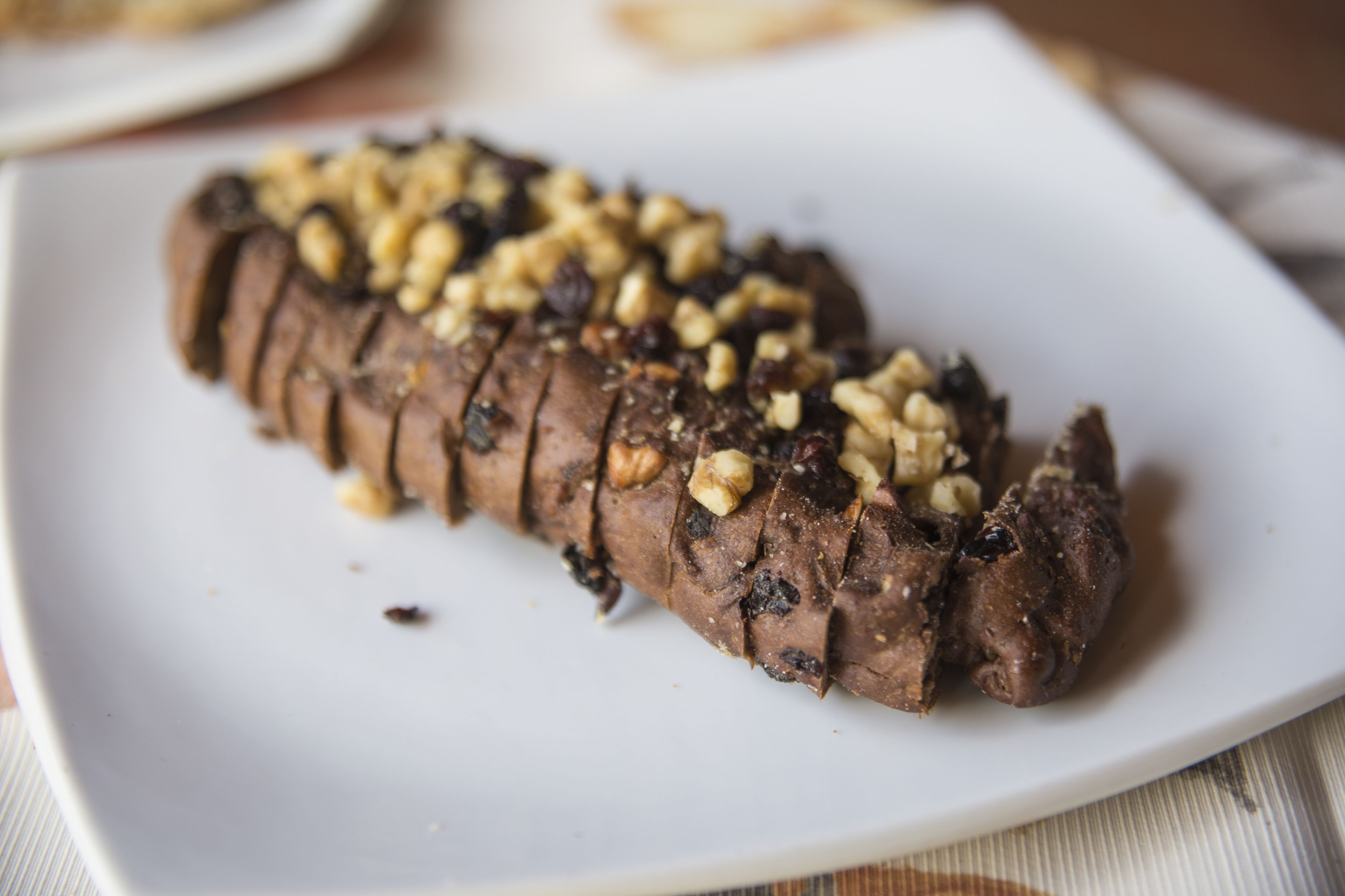 Una rebanada de pan con nueces sobre un plato blanco.