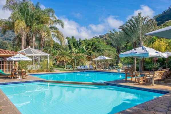 Een buitenzwembad, parasols bij het zwembad en ligstoelen