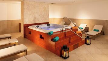 A spa room with a hot tub, wooden steps, and lounge chairs.