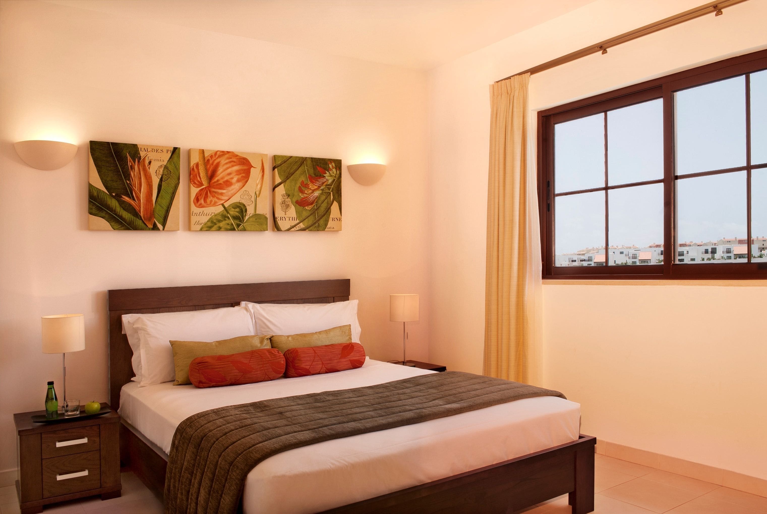 Un dormitorio ordenado con cama, mesitas de noche y decoración en la pared.