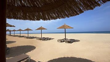 On the beach, white sand, beach cabanas, sun-loungers