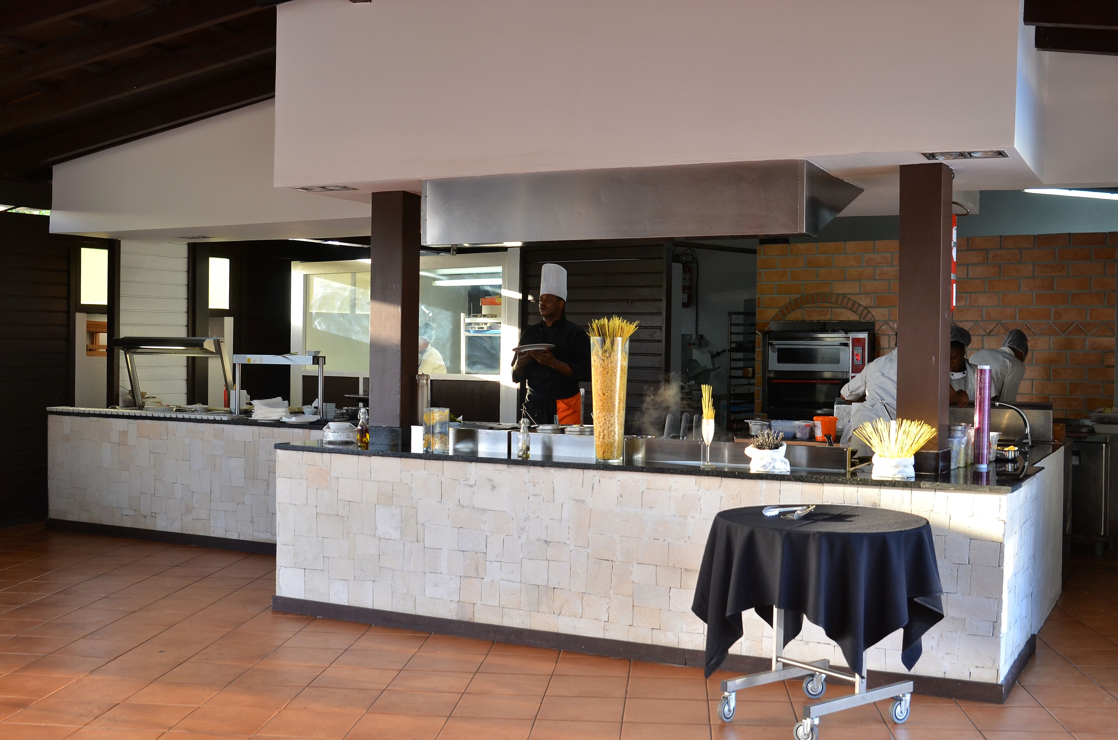 A restaurant with a stone counter, a black table with a cloth, and a brick wall in the background.