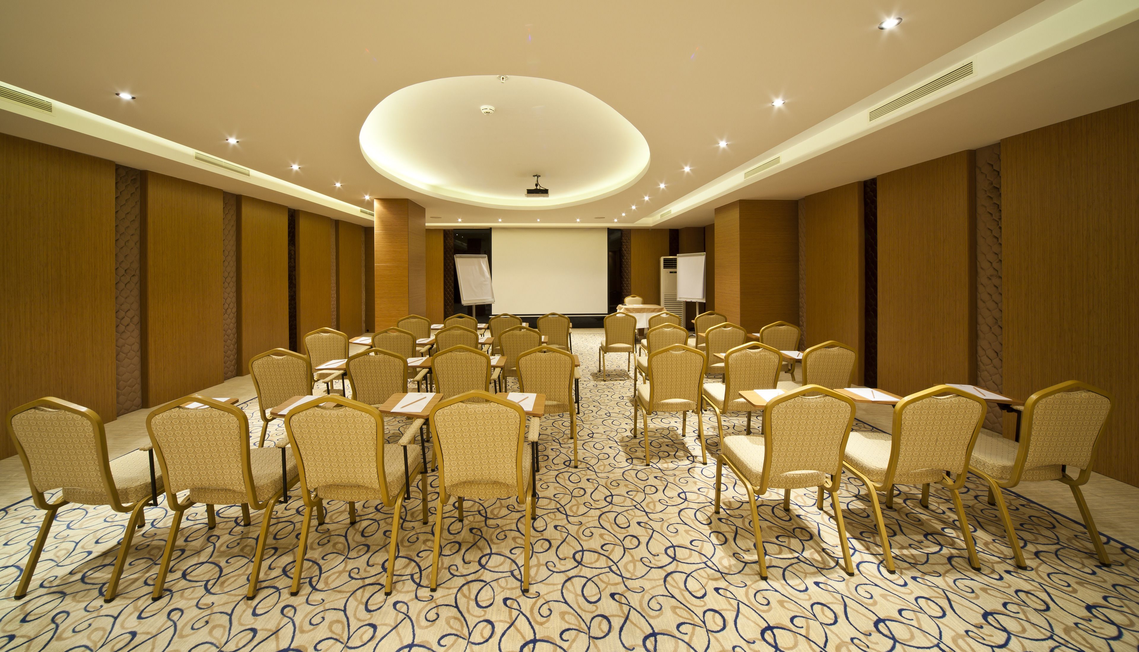 A conference room with rows of chairs, a large screen, and a podium.