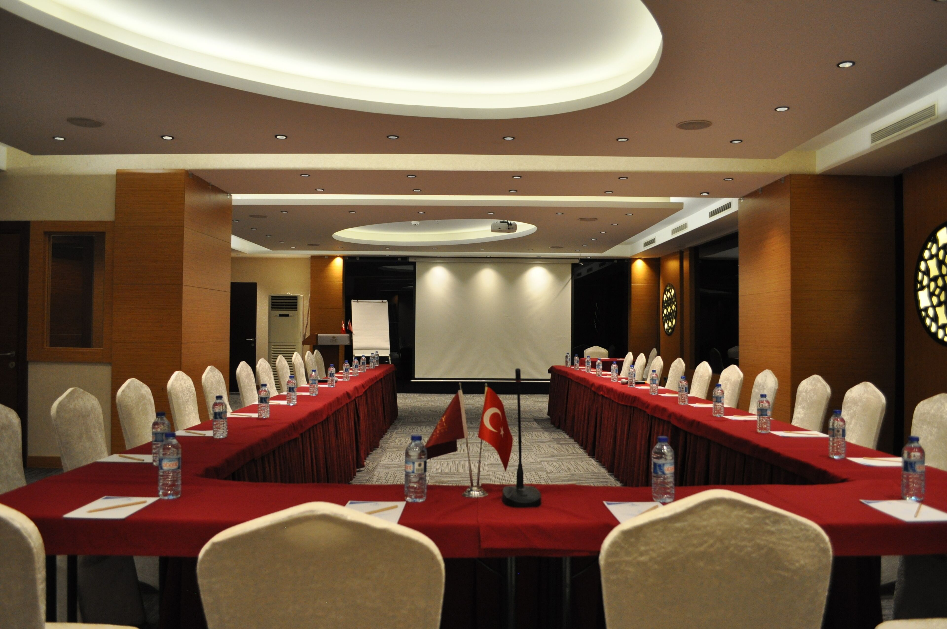 A conference room with a long table, chairs, flags, and water bottles.
