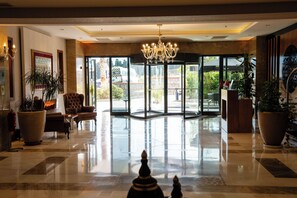 A hotel lobby with a chandelier, seating area, large potted plants, and a view through the glass doors. - Volley Hotel Istanbul (Istanbul)