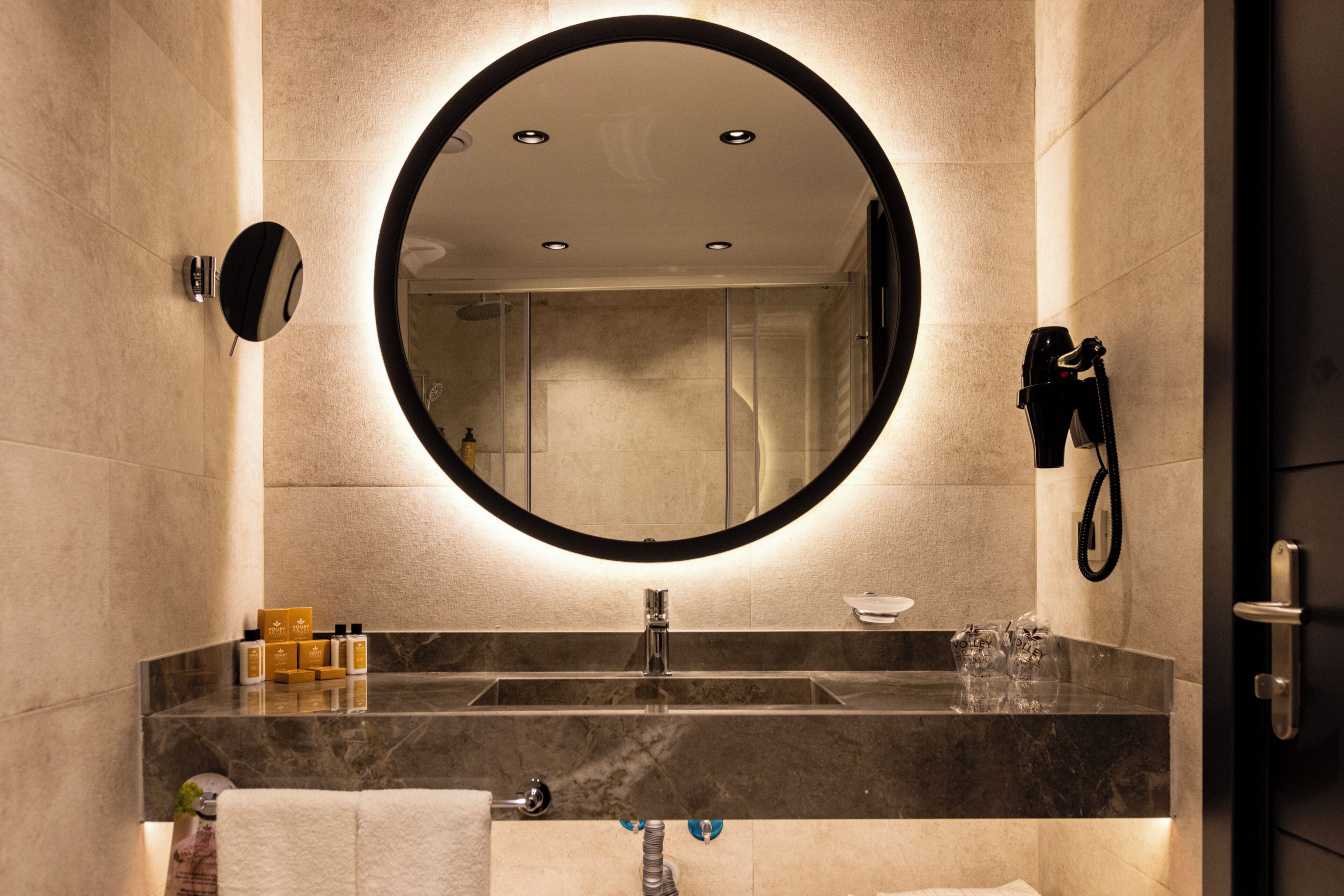 A modern bathroom with a round mirror, a sink, and a towel rack.