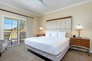 A hotel room with a large bed, two bedside tables with lamps, a ceiling fan, and a sliding glass door leading to an outdoor area. - WorldMark Reunion (Kissimmee)