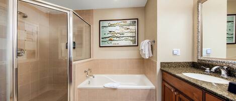 A bathroom with a glass-enclosed shower, a freestanding bathtub, a sink with a vanity, and a large mirror.
