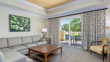 A living room with a sofa, coffee table, and a chair. There is a ceiling fan, a lamp, and a window with curtains.