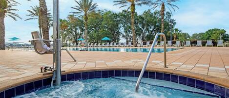 A pool area with lounge chairs and a hot tub.