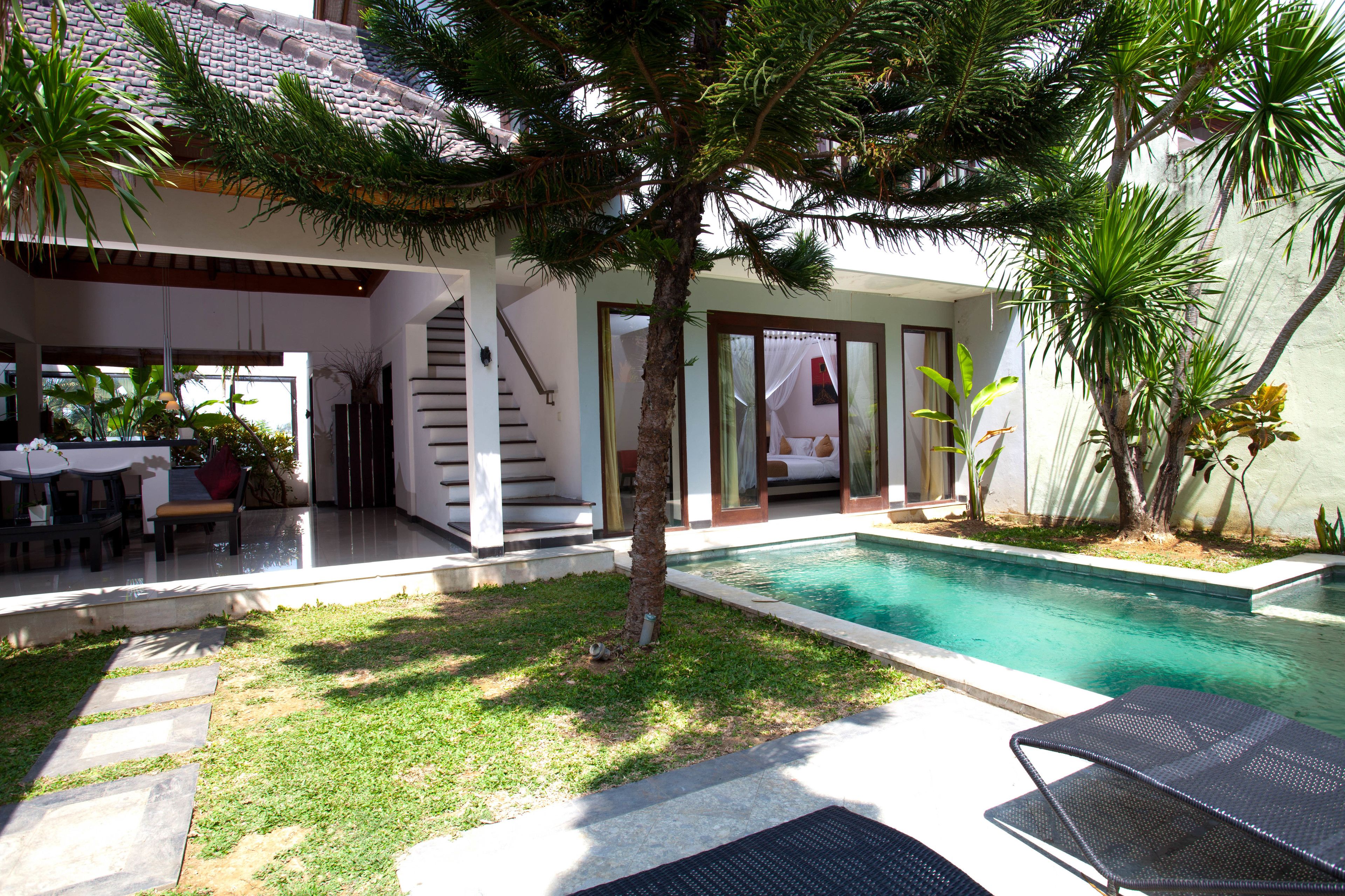 Ein Poolbereich mit freiem Blick auf den Pool, eine überdachte Sitzgelegenheit und eine Treppe, die zu einer oberen Ebene führt.