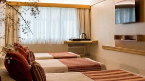 A hotel room with two beds, a television, a small table with a kettle, and a window with curtains. - Hotel Solans Republica (Rosario)