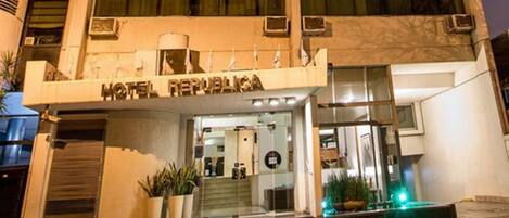 A hotel named "Hotel Republica" with a modern facade, large windows, and a visible entrance with potted plants.