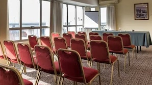 A conference room with rows of red chairs, a table with a blue tablecloth, and large windows offering a view of the city. - Hotel Solans Republica (Rosario)