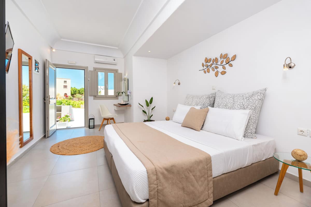 A bedroom with a bed, a bedside table, a chair, a window, and a door leading to a balcony.