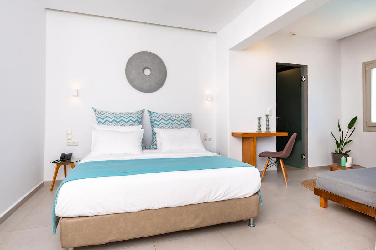 A modern bedroom with a large bed, a desk, and a chair.