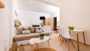 A modern living room with a sofa, coffee table, and dining area. - Hotel Kalisperis (Santorini)