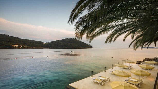 A beachside resort with a pool area, lounge chairs, and umbrellas. - Aminess Lume Hotel (Smokvica)