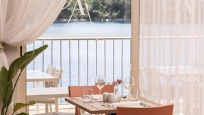 A dining area with a table set for two, overlooking a body of water. - Aminess Lume Hotel (Smokvica)