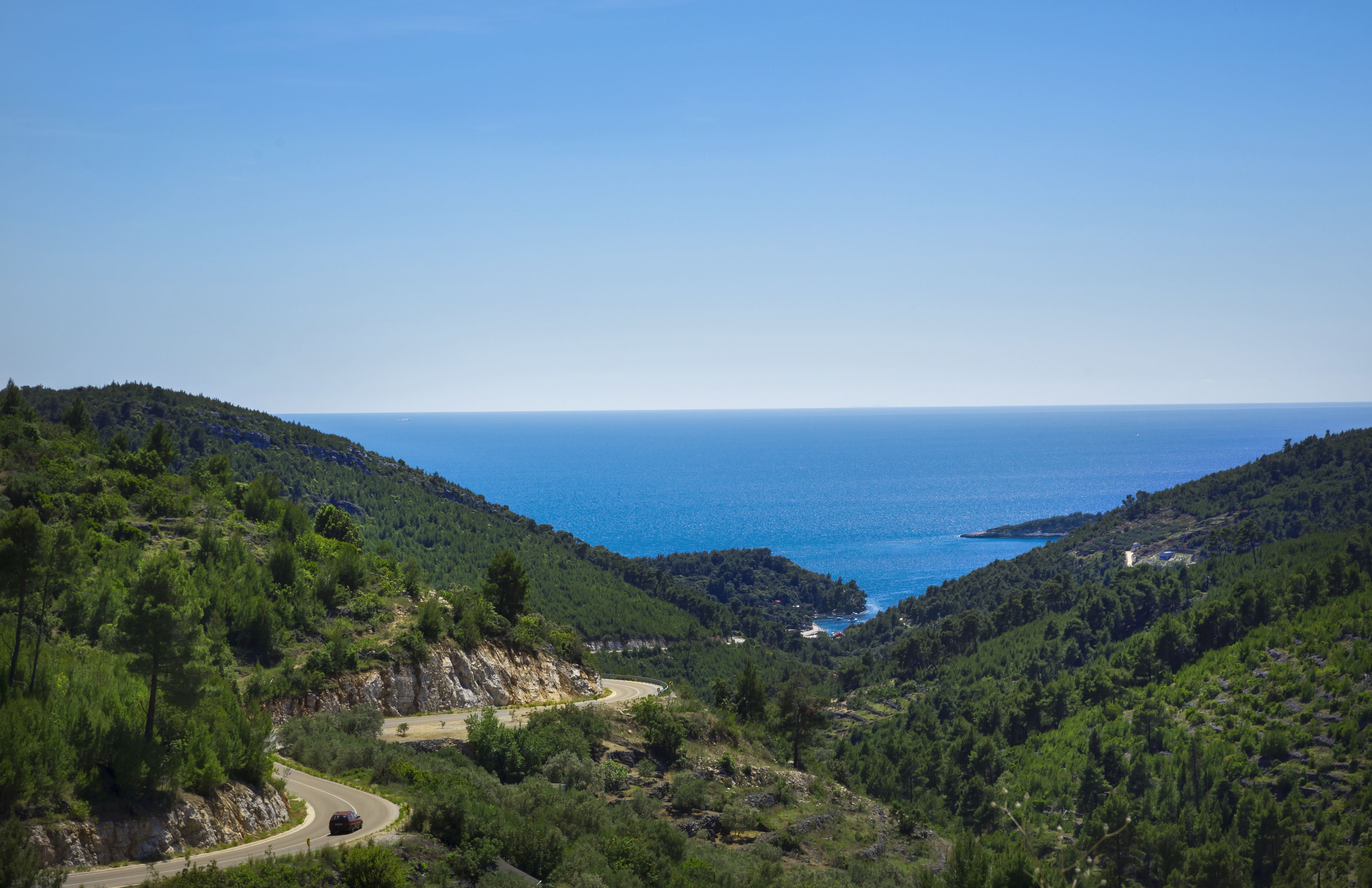 A coastal road winding through a mountainous area with a view of the sea.