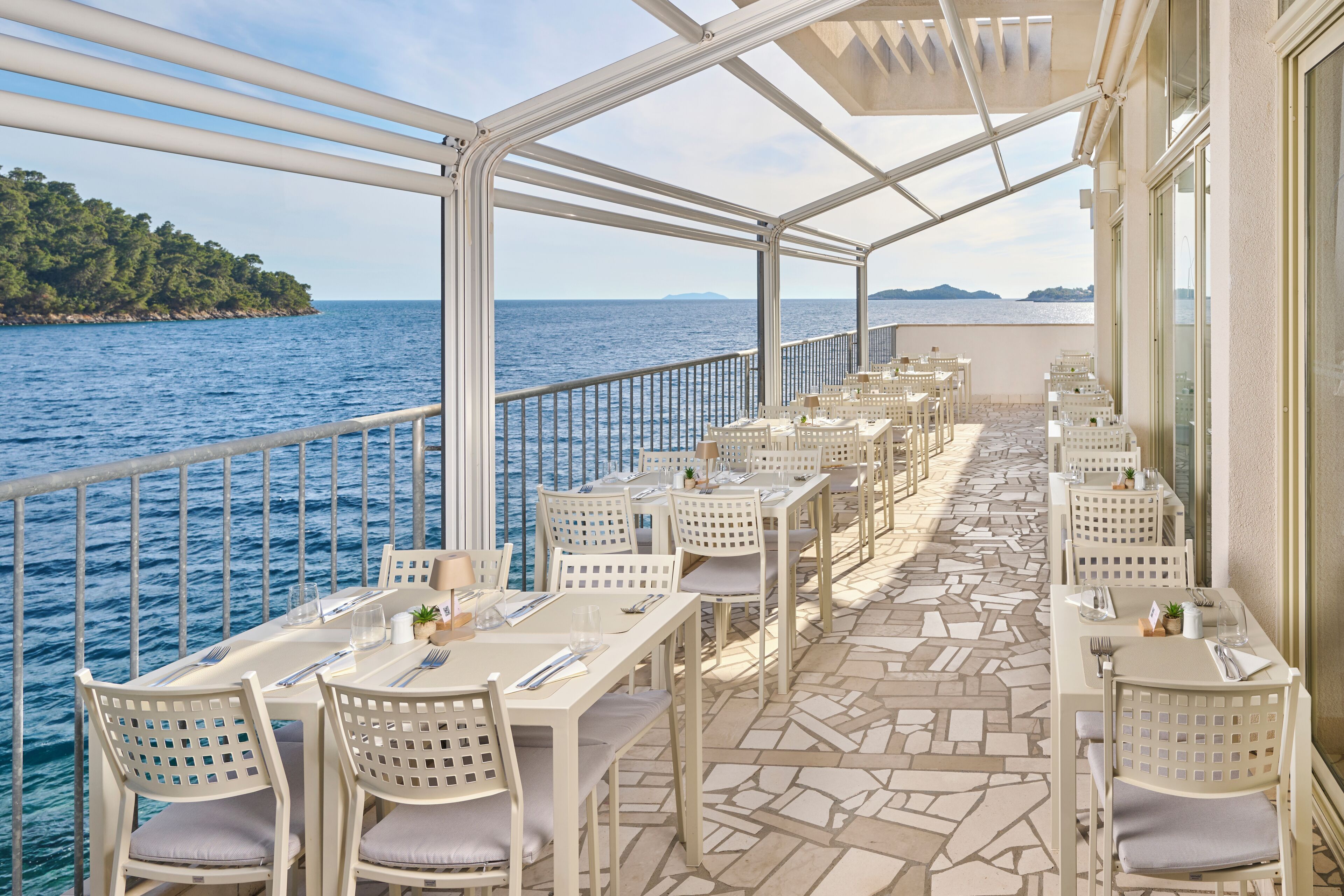 A deck with tables and chairs, overlooking the sea.