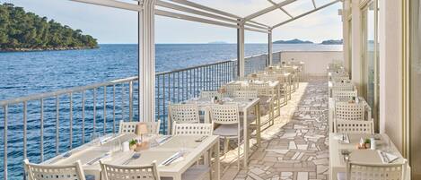 A deck with tables and chairs, overlooking the sea.