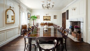 A formal dining room with a long wooden table, ornate chairs, a chandelier, and a fireplace. - Compton House (Axbridge)
