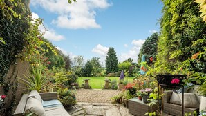 A garden patio with stone flooring, outdoor furniture, and various plants. - Compton House (Axbridge)