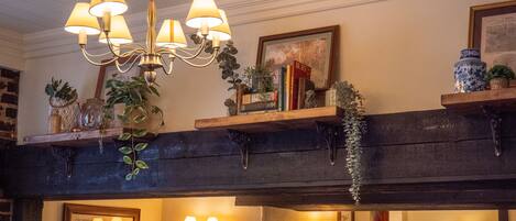 A dining area with wooden beams, chandeliers, and wall-mounted lamps.