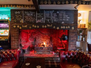 A cozy pub with a brick fireplace, leather seating, and a chalkboard menu. - The Jolly Drover (Liss)