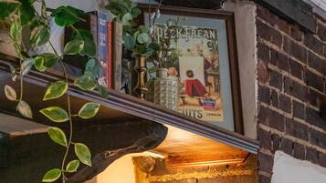 Pared de ladrillo con un cartel enmarcado, una planta colgante y una lámpara fijada a la pared.