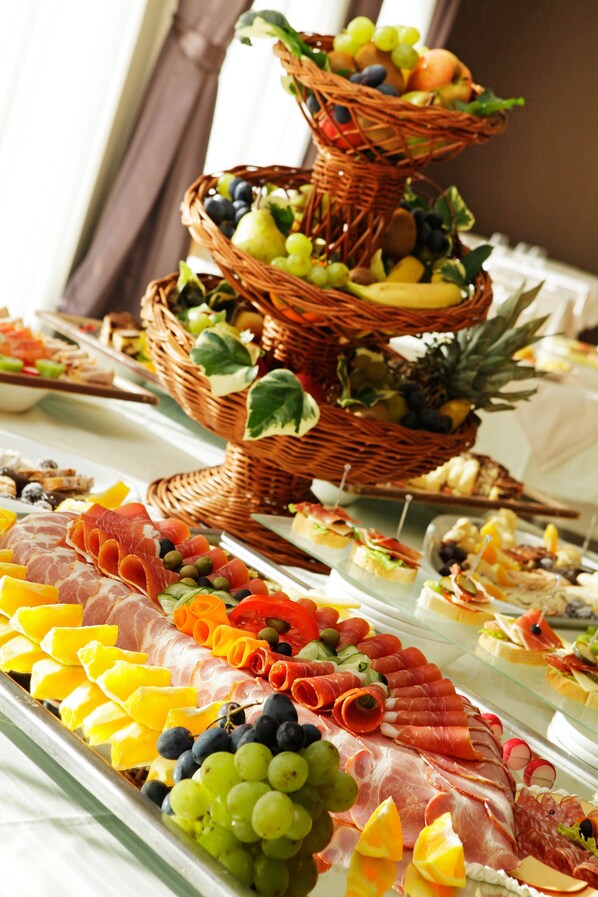 A buffet with various food items including fruits, cheeses, and meats.