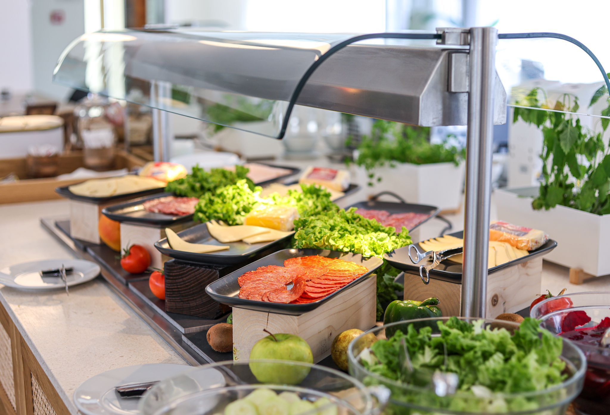 Un bufé con diversas opciones de comida, incluyendo carnes, quesos y verduras frescas.