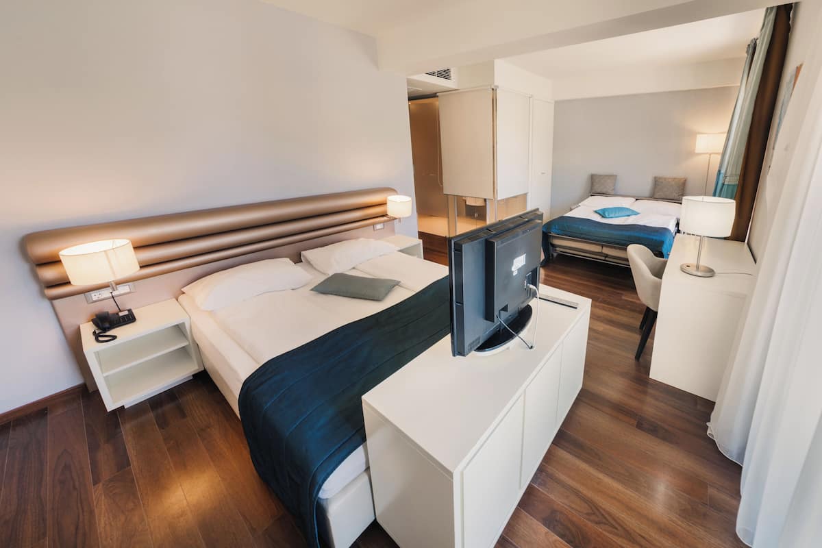 Une chambre d’hôtel comprenant un lit, un bureau avec une télévision, une chaise et une lampe de bureau.